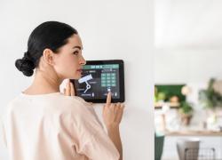 femeie care utilizeaza un panou de control acces pentru securitatea locuintei